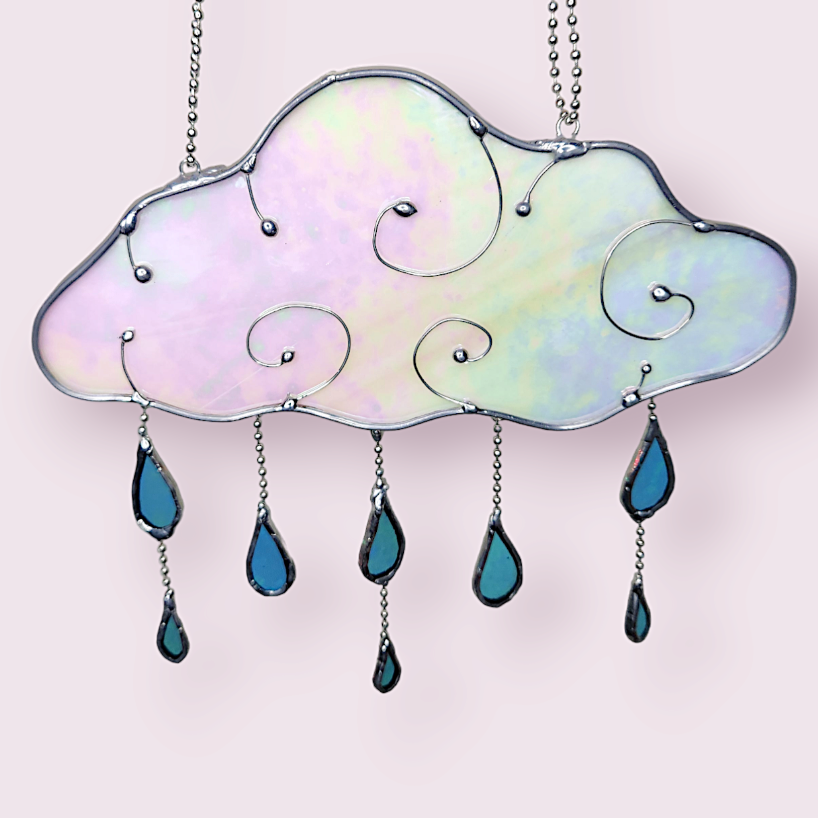 Rain Cloud Suncatcher - Sugar & Spice Crafts. Front view of hanging rain cloud and dangling blue drops. The cloud has wire swirls and iridescent glass.