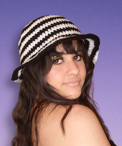 Black and white spiral bucket hat on model looking over shoulder at camera.